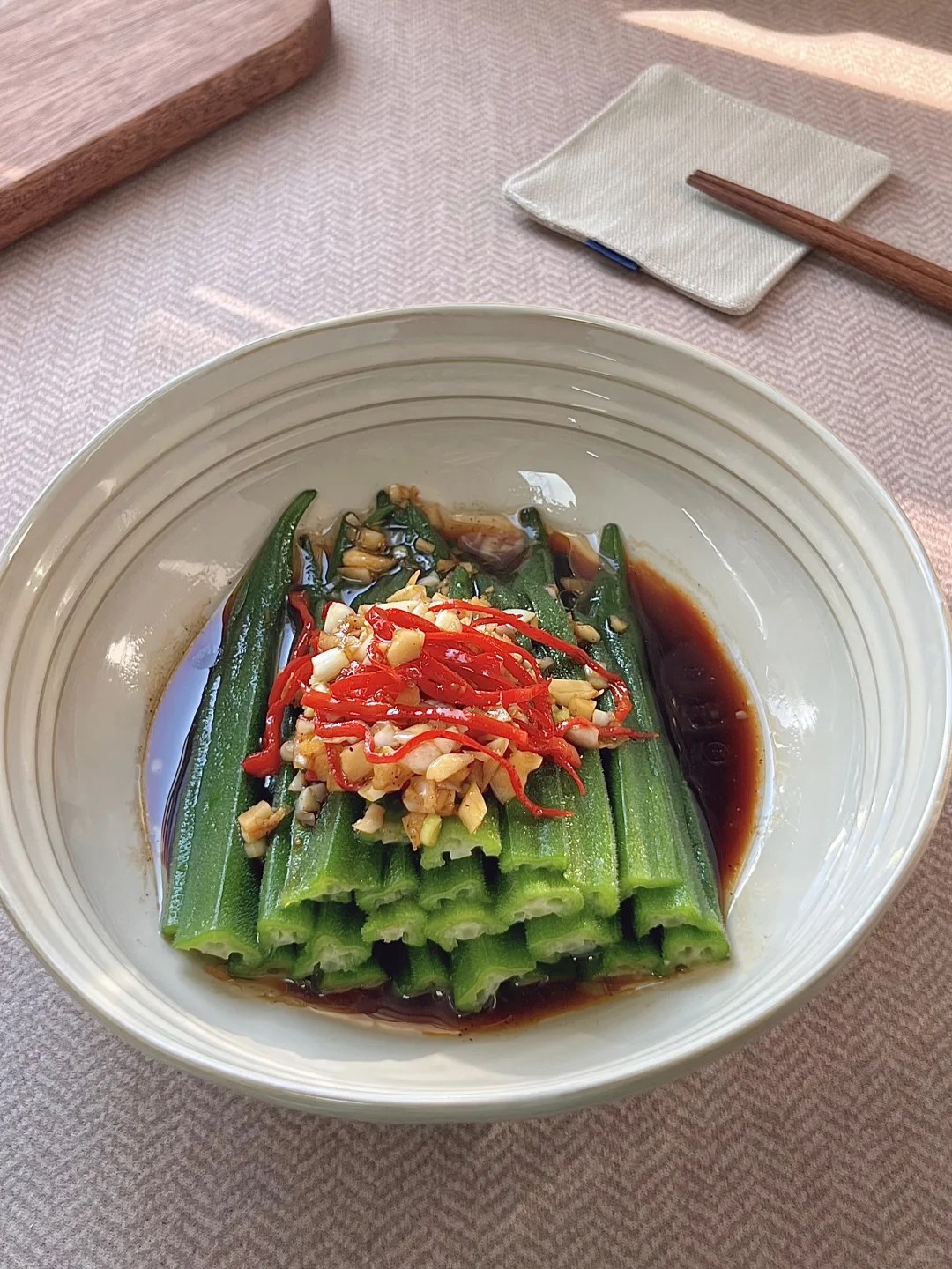 Split green okra arranged on a plate with garlic and red pepper.
