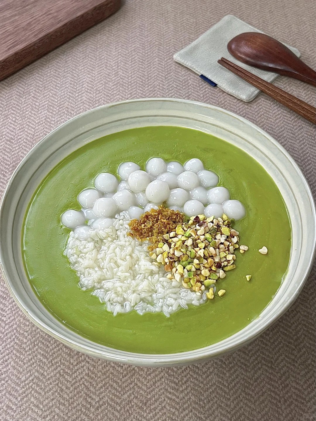 Pale green pistachio dessert with rice balls and chopped nuts.
