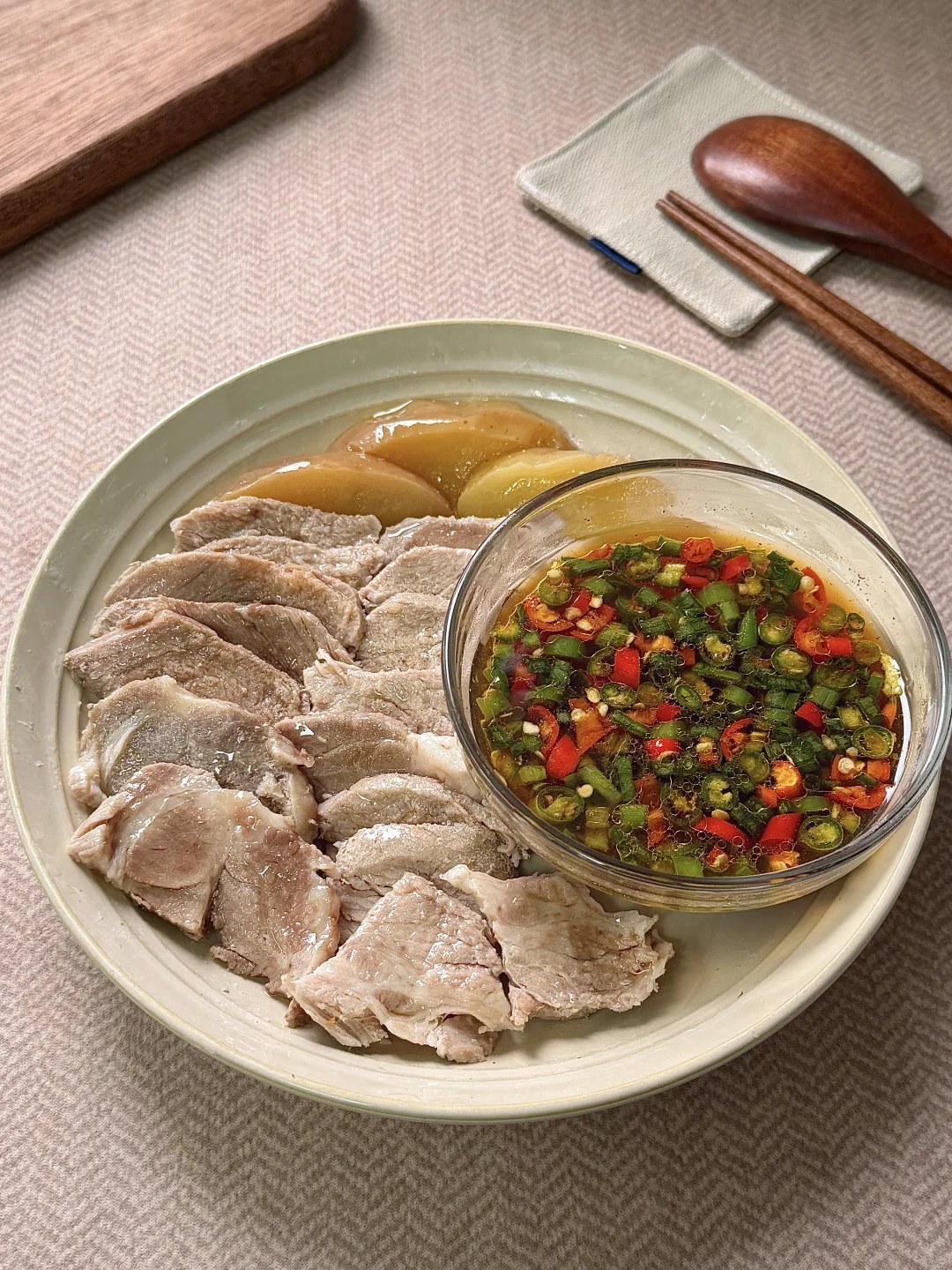 Sliced cooked pork beside a chile dipping sauce.