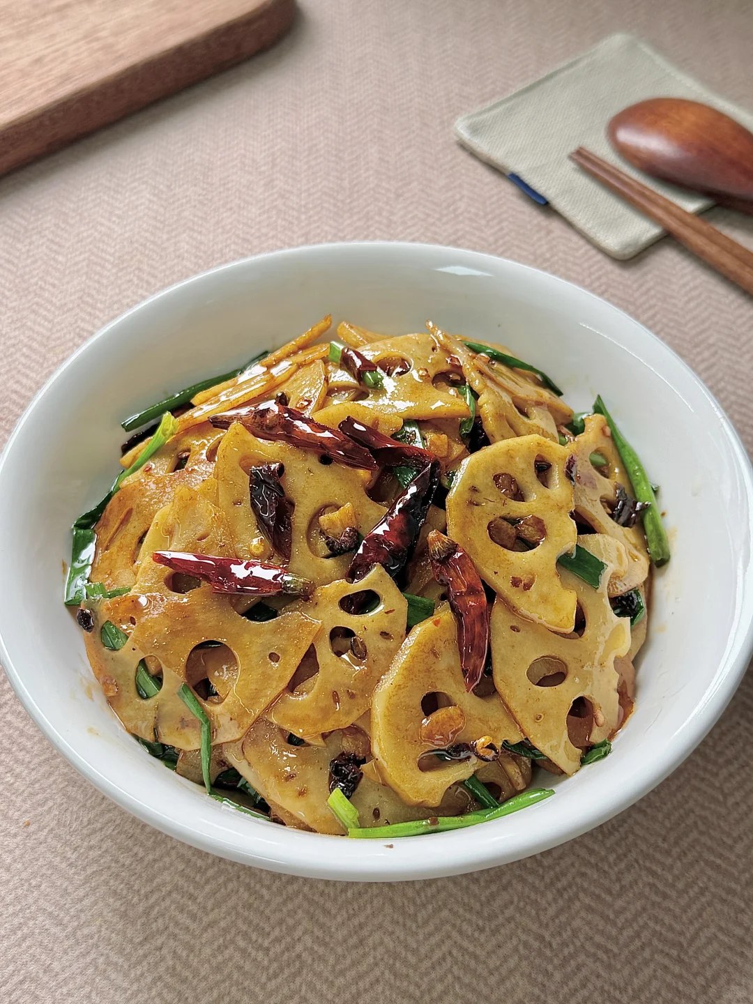 Lotus root slices with dried chiles and scallions in a pan.