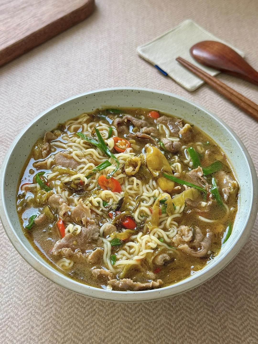 Beef slices and noodles with pickled greens in broth.