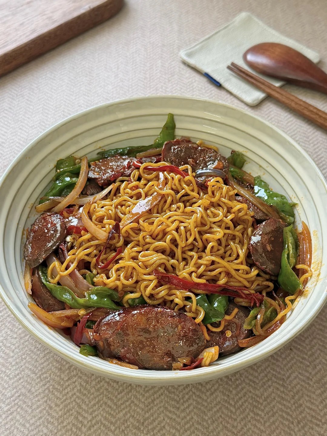 Instant noodles with curled sausage slices and green pepper.