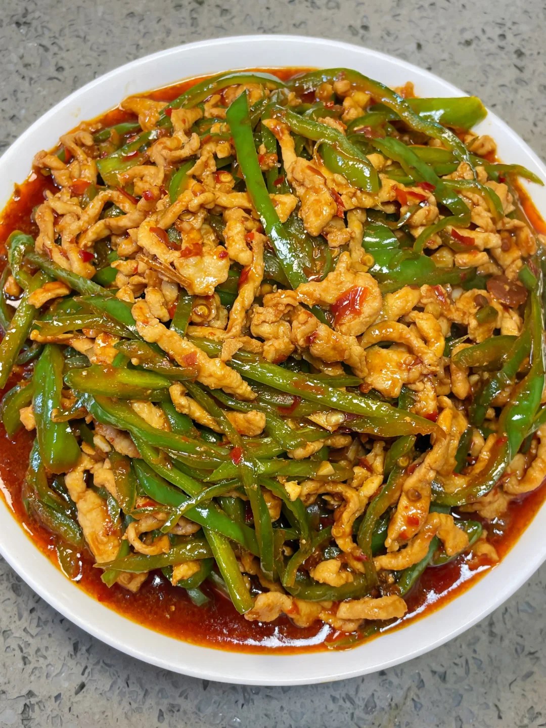 Thin pork strips and green pepper strips in a glossy sauce topped with green scallions.