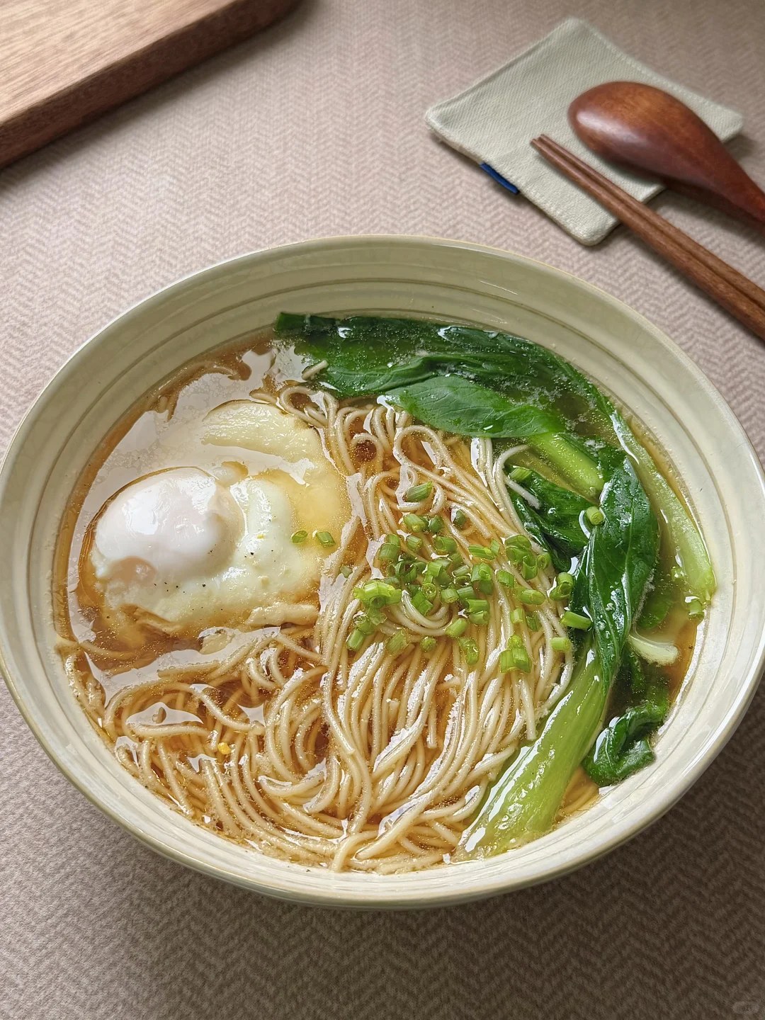 Noodles with egg and leafy greens in a bowl of clear broth.