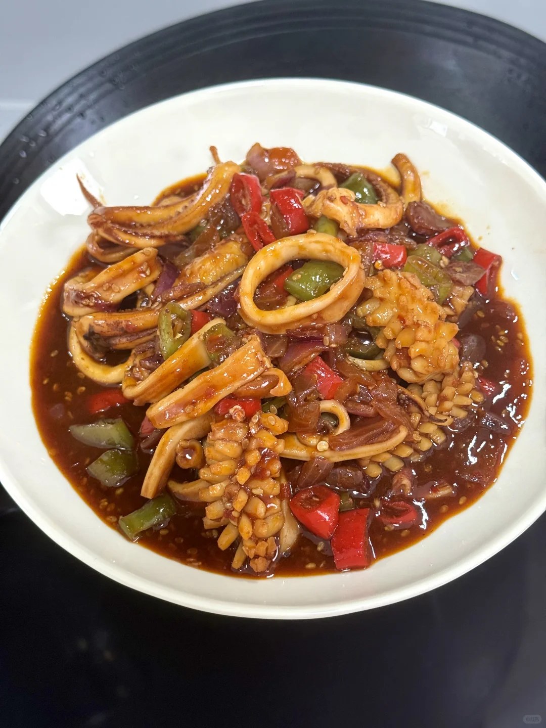 Squid pieces and onion rings in a dark red chile sauce.