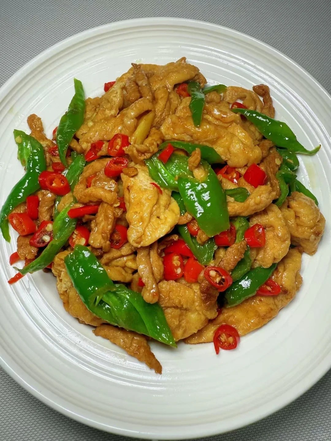 Golden tofu puff pieces with pork strips and green and red peppers.
