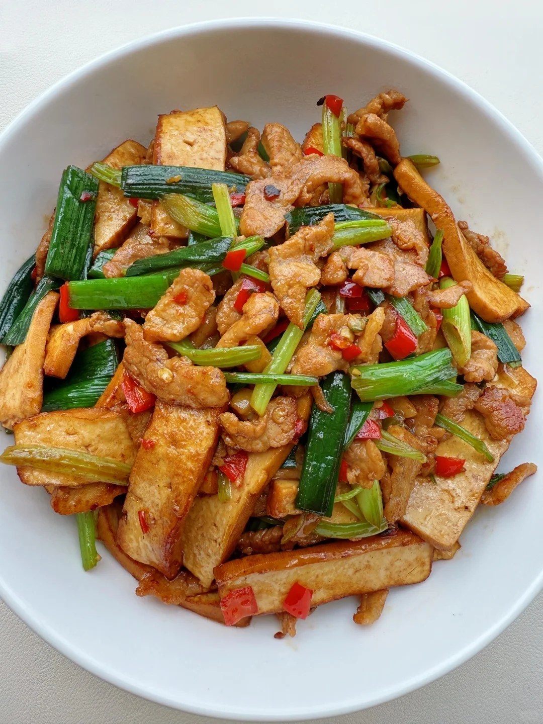 Brown pressed tofu strips with pork, celery and green garlic sections.